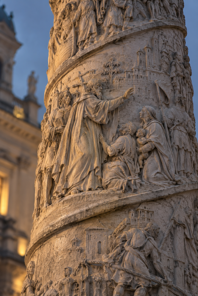 KI-generierte Nahansicht eines steinernen Säulenreliefs mit Figuren und Gewandfalten im warmen Seitenlicht.